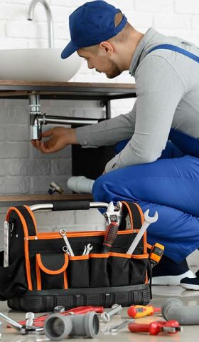 Handsome plumber repairing sink in bathroom