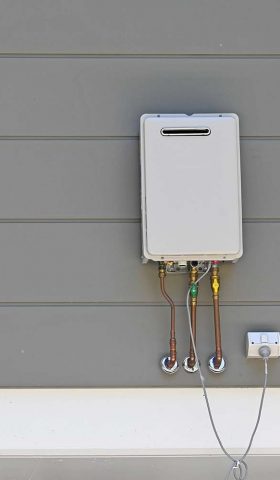 Instantaneous gas hot water heater on the side of a house