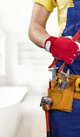 plumber with tool belt standing in bathroom