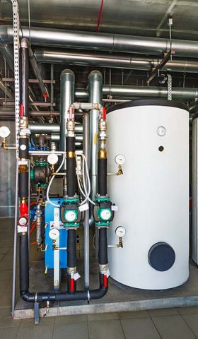 The interior of a modern gas boiler house with pumps, valves, a multitude of sensors and barrels.